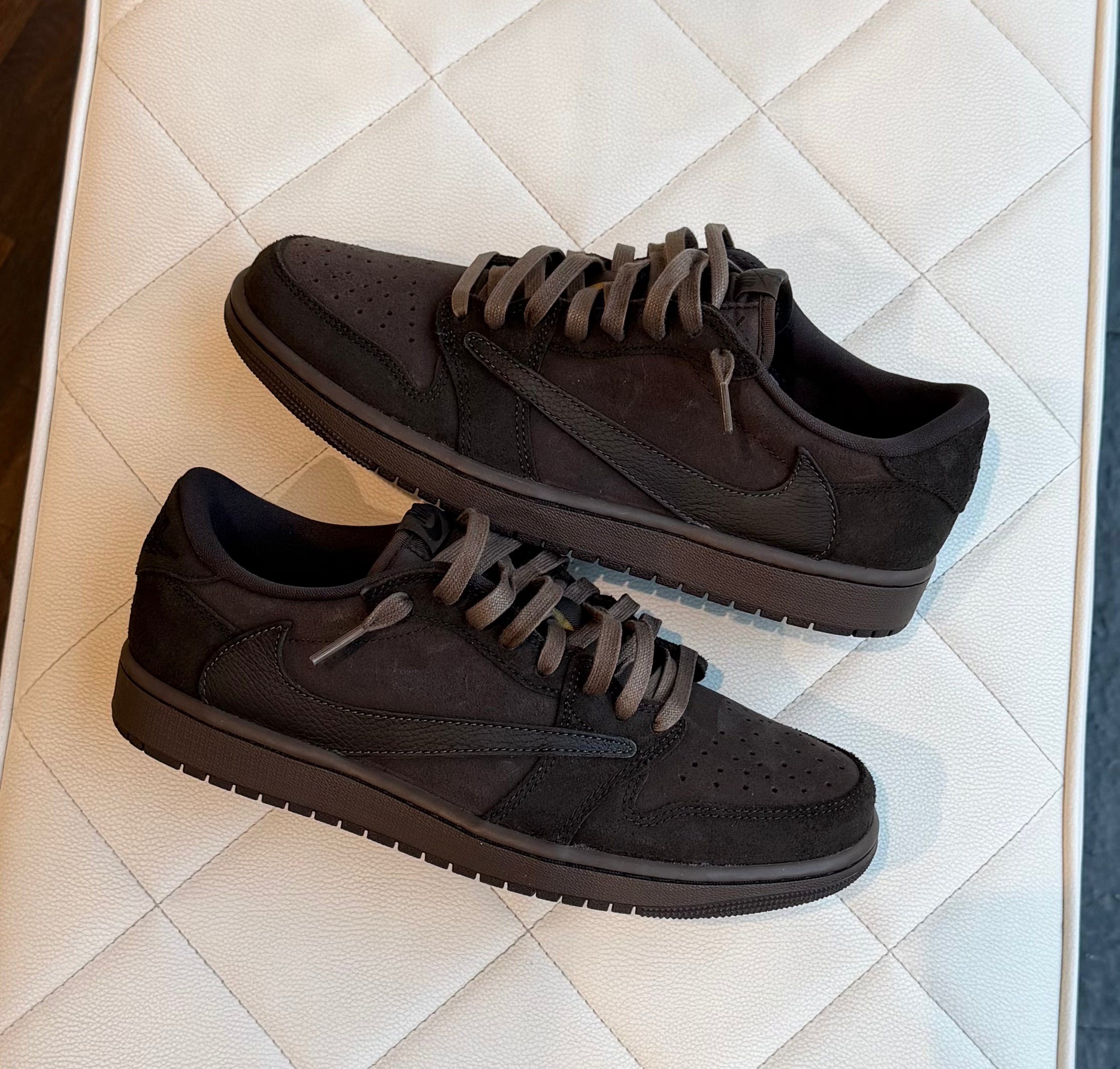 Travis Scott x Air Jordan 1 Low Velvet Brown real life in-store foto van de sneaker liggend in de winkel met velvet brown suède overlays, donkere details en de iconische reversed Swoosh duidelijk zichtbaar.